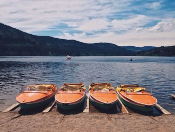 Boats moored on pier by lake titisee against sky