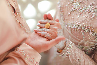 Midsection of bridegroom holding hands during wedding ceremony