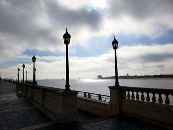 Street light by building against cloudy sky