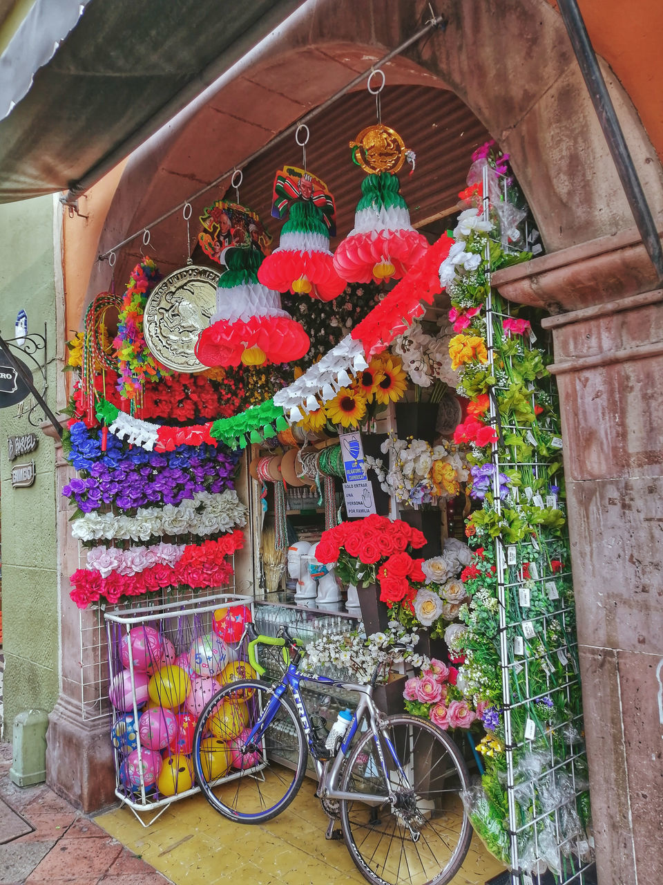 multi colored, architecture, bicycle, flower, flowering plant, no people, building exterior, built structure, day, art, plant, decoration, transportation, outdoors, nature, city, building, retail, hanging, small business, travel