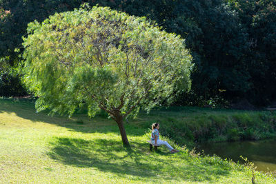 Side view of woman on grass against trees