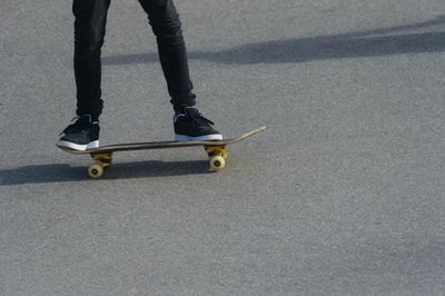 Low section of man skateboarding on road