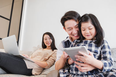 Happy friends looking away while sitting on mobile phone