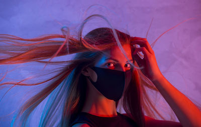 Portrait of woman wearing mask against purple background