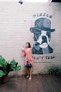 Full length of woman standing against wall