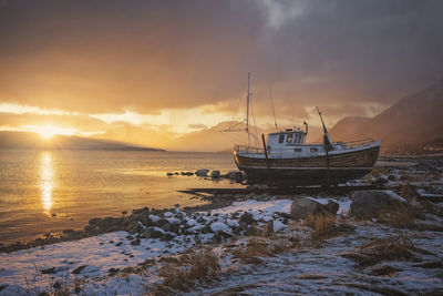 Norwegian wooden boat beached at sunset with snow