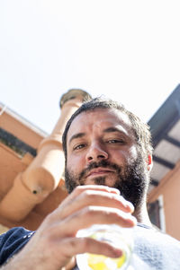 Close up of a guy with black beard and cocktail, shooting from below