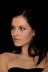 Close-up portrait of a young woman over black background
