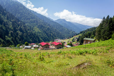 Houses on field by mountains against sky