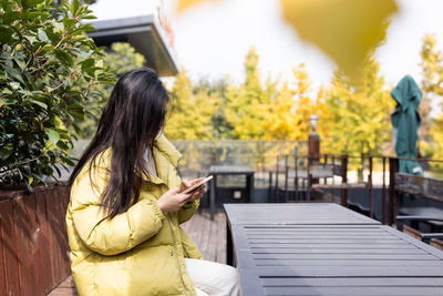 Woman using phone sitting on bench