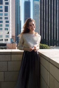 Portrait of young woman standing against building