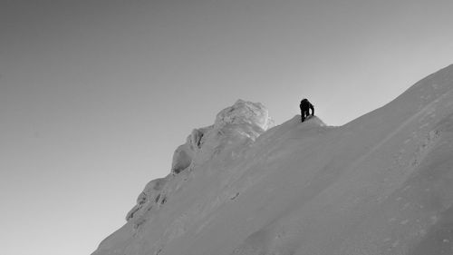 Low angle view of person on mountain against clear sky