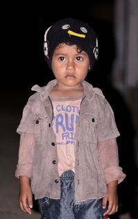 Portrait of cute boy looking away against black background
