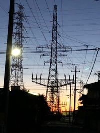 Low angle view of electricity pylon against sky during sunset