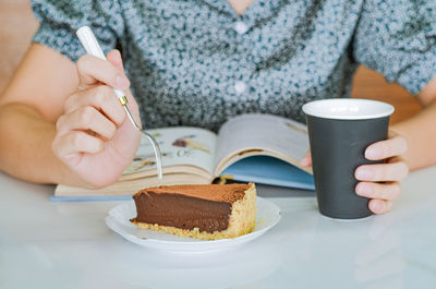 Midsection of woman eating dessert on table