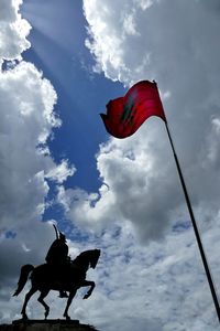 Low angle view of skanderbeg monument with albanian flag against sky