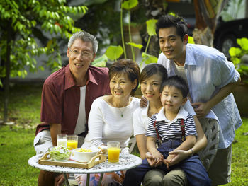 Happy family with breakfast on table at back yard