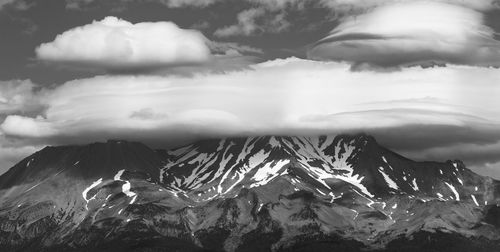 Scenic view of dramatic mountains against sky and lenticular cloud