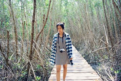 Woman standing on footbridge in forest