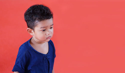 Baby boy standing against red background