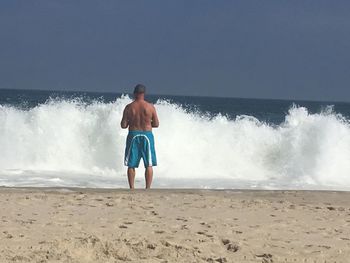 Full length of man standing at beach against clear sky