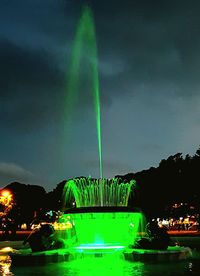 Illuminated fountain in front of building against sky at night