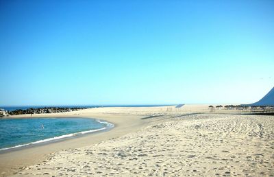 Scenic view of beach against clear blue sky