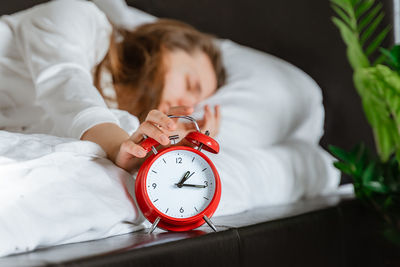 Woman sleeping in bed turns off alarm clock wake up at morning, hand pressing snooze  healthy day 