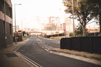 Road by buildings in city against sky