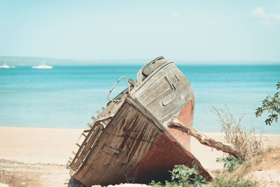 Abandoned boat on beach against sky