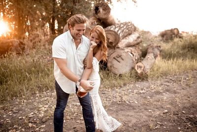 Full length of couple with champagne bottle in a field. 