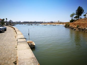 Boats moored at river against clear blue sky