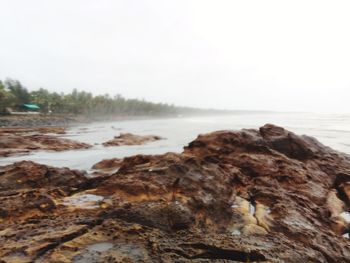 Scenic view of sea and rocks against clear sky