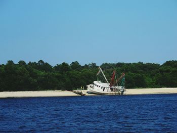 Boat sailing in sea against clear sky