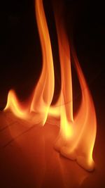 Close-up of burning candle against black background