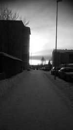 Road by city against sky during sunset