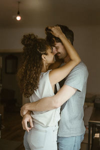 Girlfriend rubbing nose with boyfriend standing at home