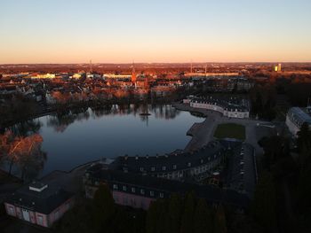 High angle view of river amidst buildings against sky at sunset