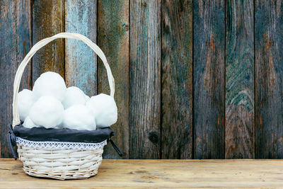 White wicker basket with snowballs on wooden retro grunge background made of barn board 