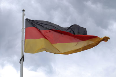 Spain flag at a flagpole moving in the wind against the sky