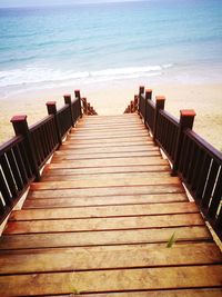 Wooden pier on beach against sky