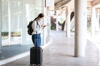 Woman wearing mask using mobile phone at airport