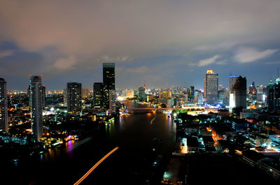 Illuminated modern buildings in city against sky at night