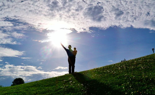 People standing on field against cloudy sky