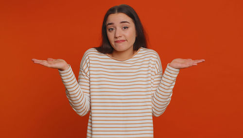 Portrait of young woman standing against yellow background