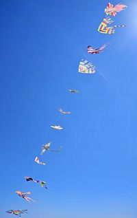 Low angle view of kites against clear blue sky