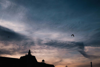 Low angle view of silhouette birds flying against sky