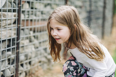 Young girl crouching down and looking for bugs in a rock wall