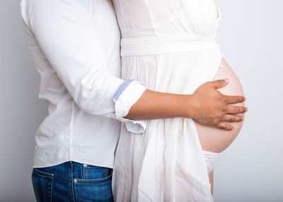 Midsection of woman standing against white wall