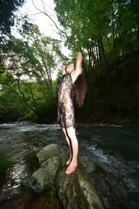 Woman standing on rock by river in forest